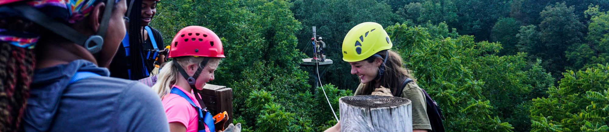 Woman smiling as she guides zipliners high above the trees at Canaan Zipline Canopy Tours near Charlotte, NC